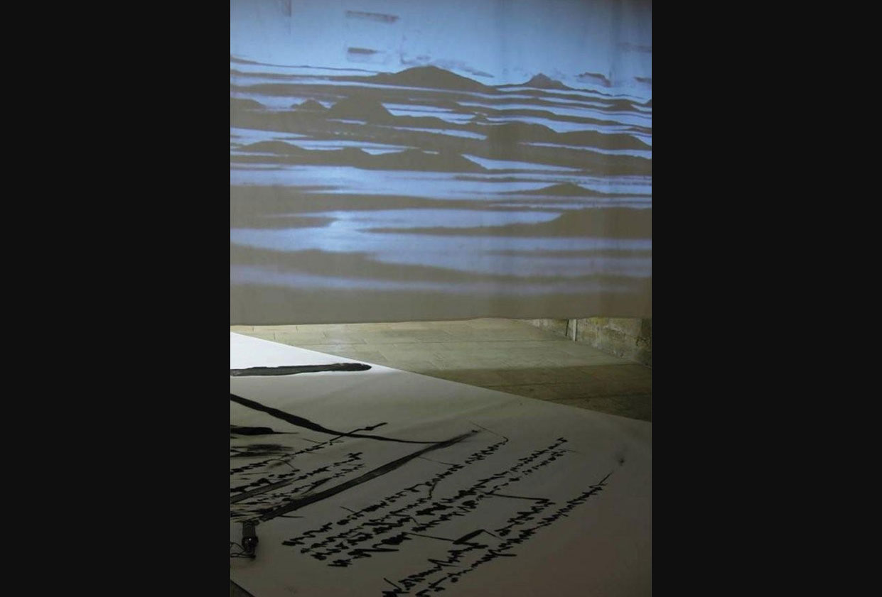 Mobile Landscape by Mr. Kim Jongku (South Korea). Medium/Material: Steel powder, CC camera, LED projector, screen, paper roll. Jongku Kim’s work begins with the arduous and meditative task of grinding solid steel poles and collecting the ground steel particles. With the steel powder, the artist writes calligraphy or quotes from foreign poetry, which is either adhered onto a canvas or loosely positioned for floor installations. The tiresome preparatory work is an indispensable step to the mental and metaphysical creativity of traditional painting and writing in which much attention and appreciation is given to the process itself.